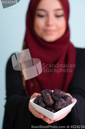 Image of modern muslim woman holding a plate of dates in ramadan kareem