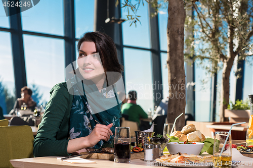 Image of young woman  having lunch at restaurant