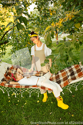 Image of The happy young family during picking apples in a garden outdoors