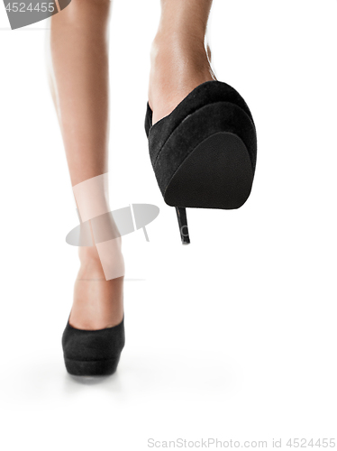 Image of Tanned female legs in high heels isolated on white background.