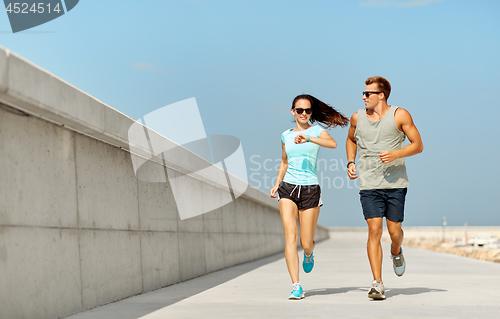 Image of couple in sports clothes running outdoors