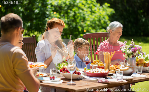 Image of happy family having dinner or summer garden party