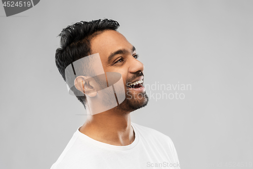 Image of young laughing indian man over gray background