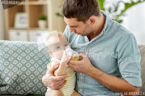 Image of father and baby drinking from bottle at home