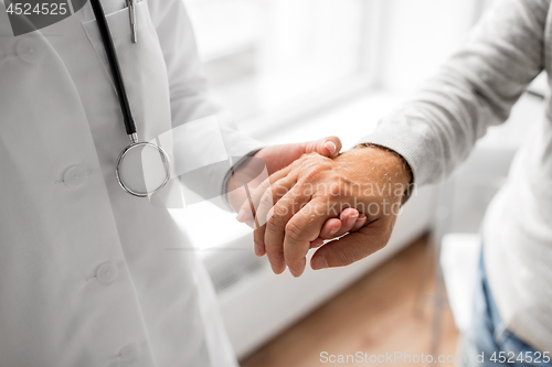 Image of close up of doctor holding senior patient hand