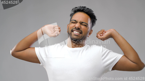 Image of indian man stretching over grey background