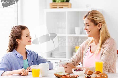 Image of happy mother and daughter having breakfast at home