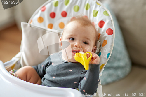 Image of baby girl with teether toy in highchair at home