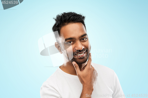 Image of smiling indian man touching his beard