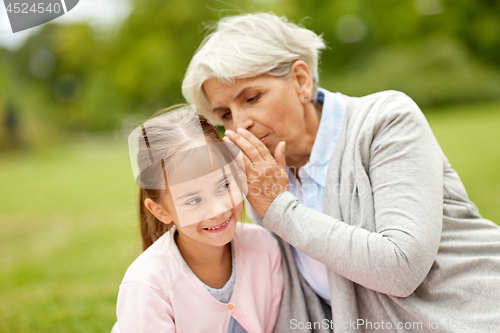Image of granddaughter sharing secrets with grandmother