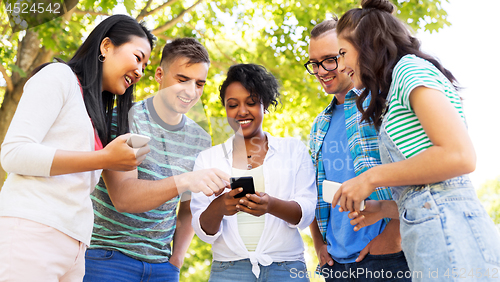 Image of happy friends with smartphones at summer park