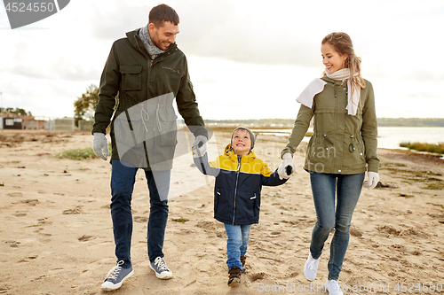 Image of happy family walking along autumn beach