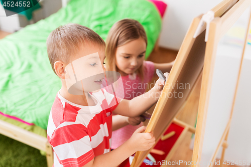 Image of happy kids drawing on easel or flip board at home