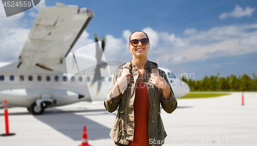 Image of young woman with backpack over plane on airfield