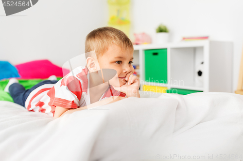 Image of happy little boy lying on bed at home