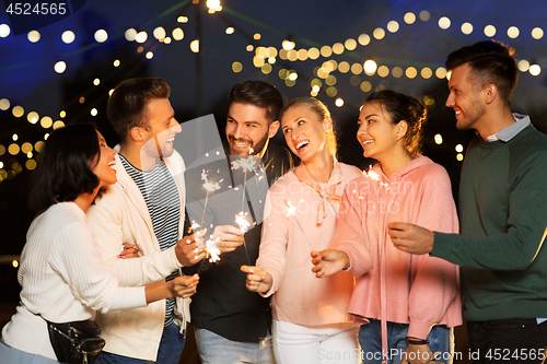 Image of happy friends with sparklers at rooftop party