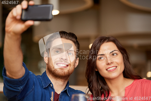 Image of couple taking selfie by smartphone at restaurant