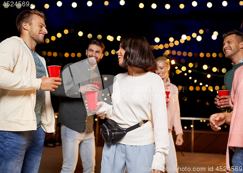 Image of friends with drinks dancing at rooftop party