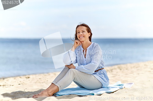 Image of happy woman sitting on summer beach