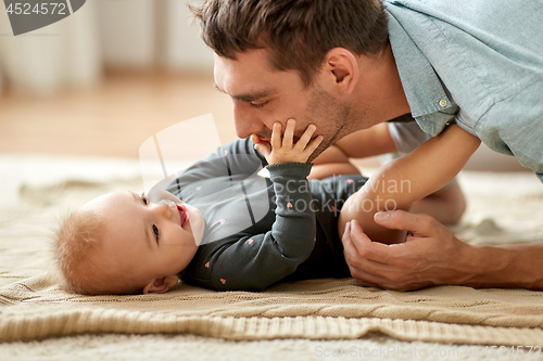 Image of father playing with little baby daughter at home