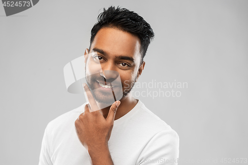 Image of smiling indian man touching his beard