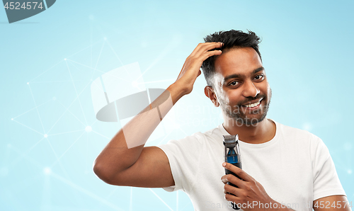 Image of smiling indian man with trimmer touching his hair