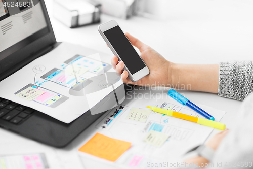 Image of web designer with smartphone and laptop at office