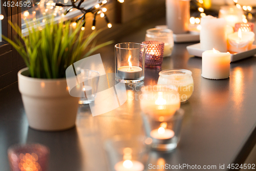 Image of candles burning on window sill with garland lights