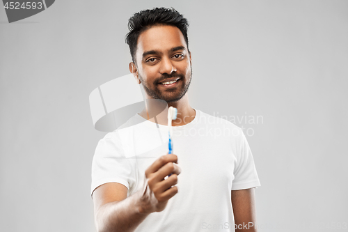 Image of indian man with toothbrush over gray background