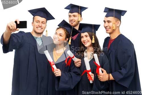 Image of graduates with diplomas taking selfie by cellphone