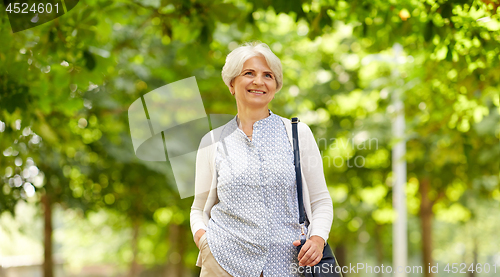 Image of happy senior woman with handbag at summer park