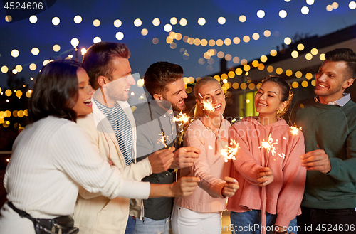 Image of happy friends with sparklers at rooftop party