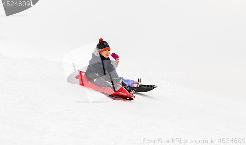 Image of happy kids sliding on sleds down hill in winter