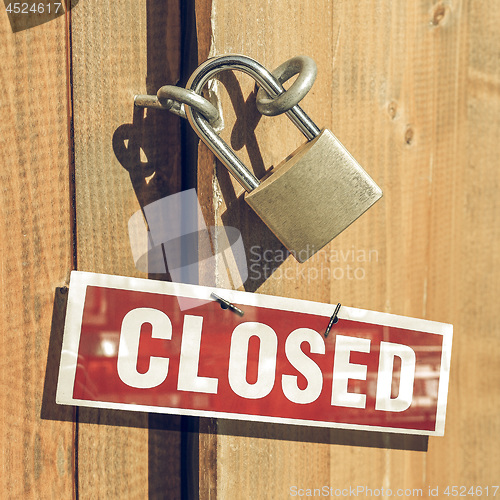 Image of Vintage looking Padlock on a wood door with closed sign