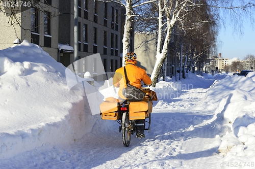 Image of the postman rides a bicycle among the snowdrifts
