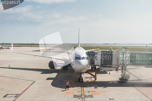 Image of Modern commercial passenger airplane parked to airport terminal building