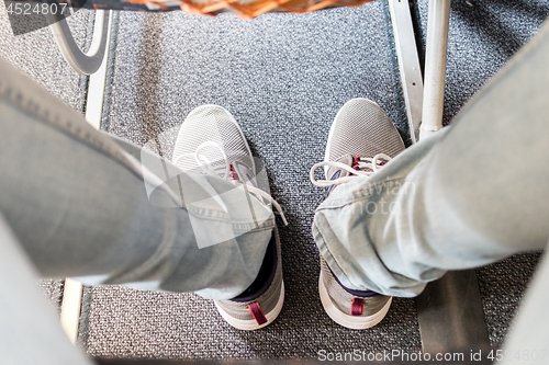 Image of Male passenger with lack of leg space on long commercial airplane flight. Focus on casual sporty sneakers