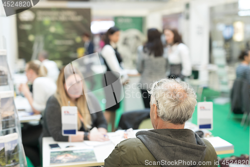 Image of Blured image of client consulting aobout product with saleswoman at business fair.