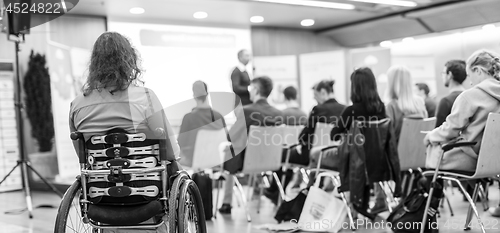 Image of Rear view of unrecognizable woman on a wheelchair participating at business conference talk.