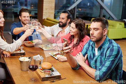 Image of man messaging on smartphone at restaurant