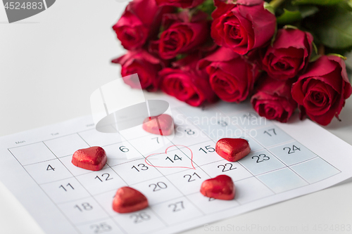 Image of close up of calendar, heart, candies and red roses