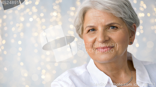 Image of portrait of senior woman over festive lights