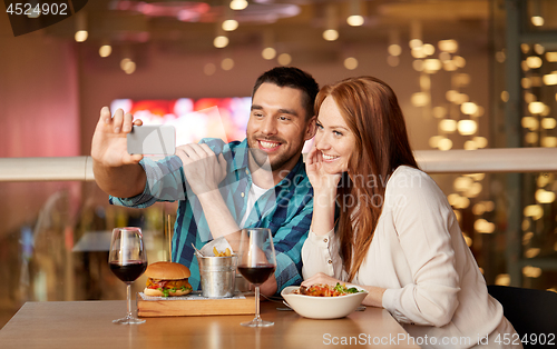 Image of couple taking selfie by smartphone at restaurant