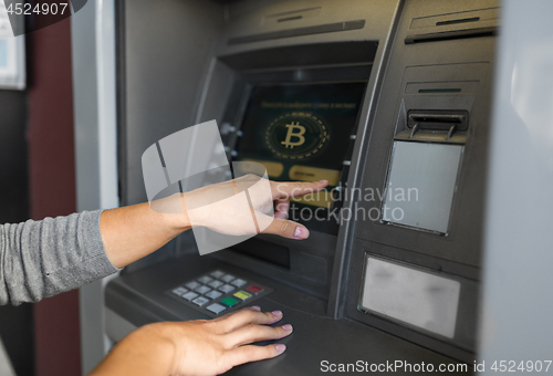 Image of woman at atm machine with bitcoin icon on screen