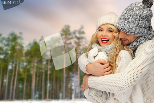 Image of couple hugging over winter forest background