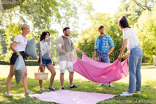 Image of friends arranging place for picnic at summer park