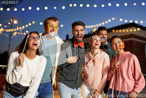 Image of happy friends with party props at rooftop