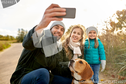 Image of happy family with dog taking selfie in autumn