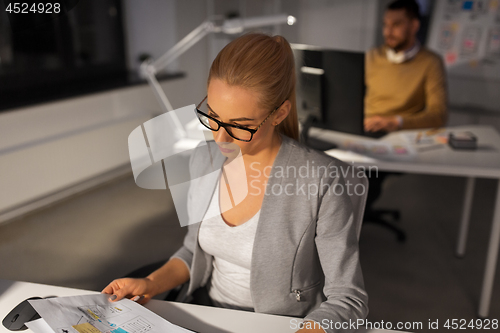 Image of designer working with papers at night office