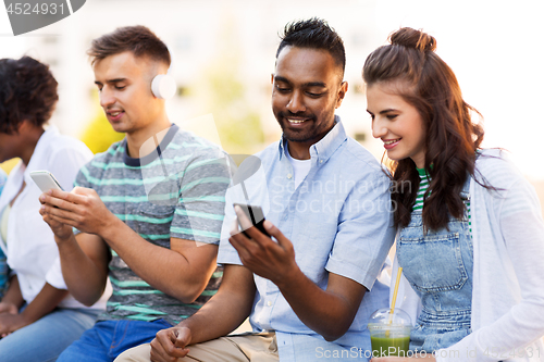 Image of friends with smartphones hanging out in summer